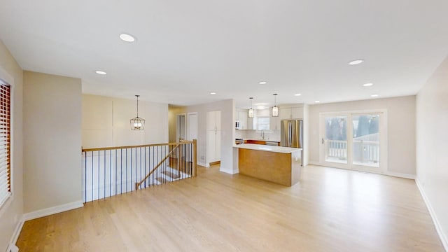 unfurnished living room with a notable chandelier and light hardwood / wood-style floors