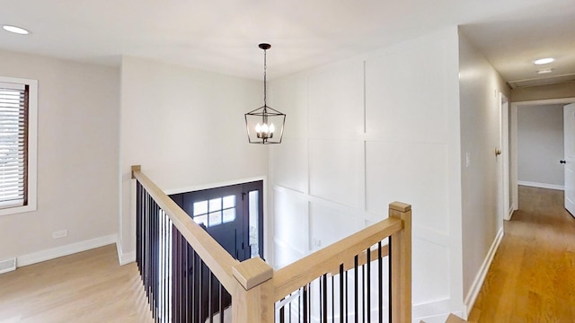 hall with a notable chandelier, plenty of natural light, and wood-type flooring