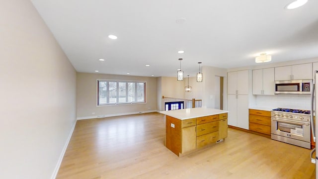 kitchen featuring white cabinets, a kitchen island, decorative light fixtures, stainless steel appliances, and decorative backsplash