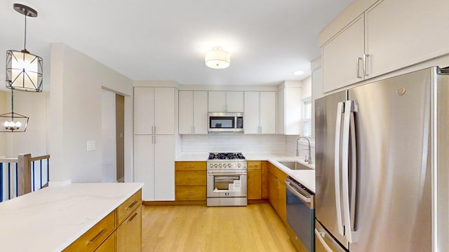 kitchen featuring hanging light fixtures, sink, backsplash, white cabinetry, and stainless steel appliances