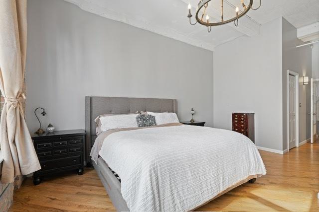 bedroom with an inviting chandelier and wood-type flooring