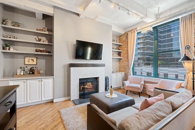 living room featuring light hardwood / wood-style flooring, track lighting, and a tiled fireplace