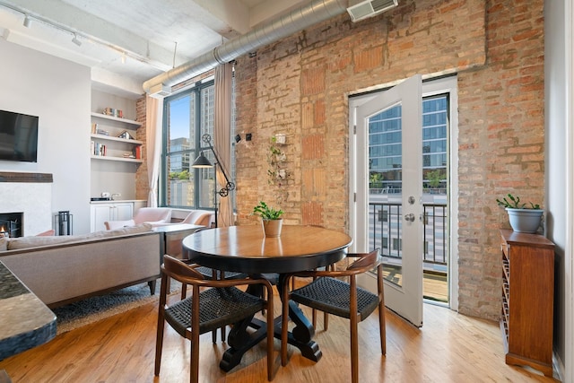 dining area with light hardwood / wood-style flooring, french doors, built in features, brick wall, and rail lighting