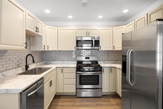 kitchen featuring backsplash, sink, stainless steel appliances, and cream cabinets