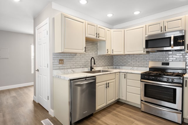 kitchen featuring decorative backsplash, appliances with stainless steel finishes, cream cabinets, and sink