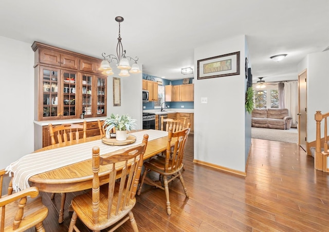 dining space featuring sink, ceiling fan with notable chandelier, and light hardwood / wood-style floors