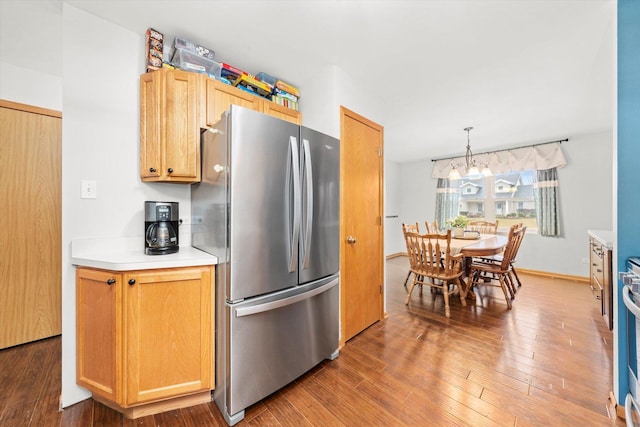 kitchen featuring dark wood-type flooring, stainless steel fridge, a chandelier, and decorative light fixtures