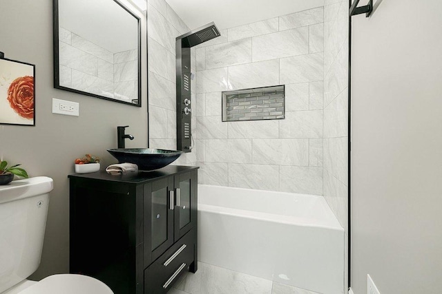 full bathroom featuring tiled shower / bath, vanity, and toilet