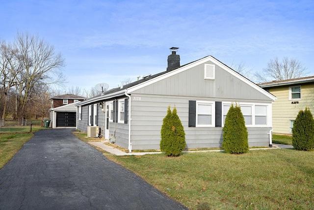 view of side of home featuring central air condition unit, a garage, an outdoor structure, and a lawn