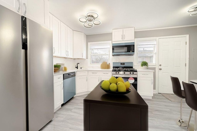 kitchen featuring white cabinets, appliances with stainless steel finishes, light hardwood / wood-style floors, and sink