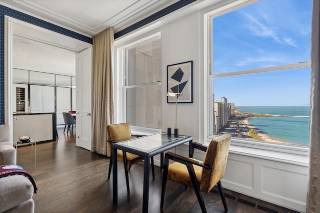 dining space featuring dark hardwood / wood-style flooring and a water view