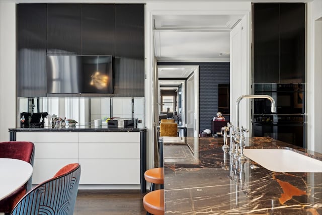 kitchen featuring white cabinets, crown molding, dark wood-type flooring, and sink