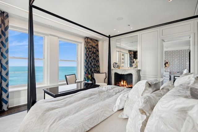 bedroom with a water view, crown molding, and multiple windows