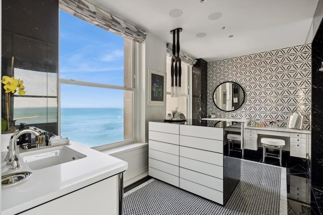 bathroom featuring sink, a water view, and a healthy amount of sunlight