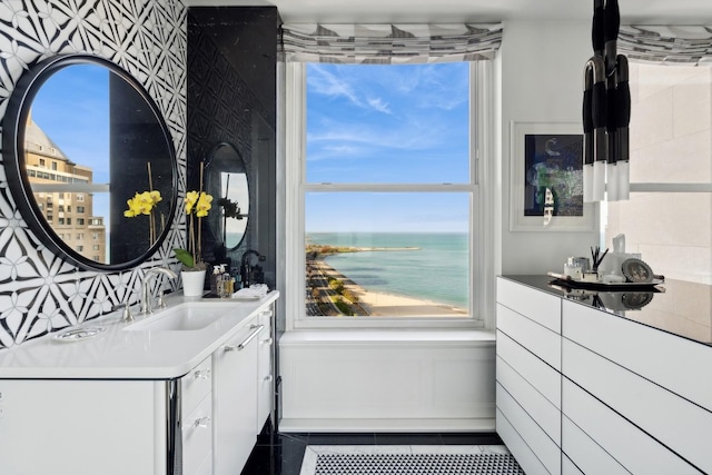 bar featuring dark tile patterned flooring, a water view, white cabinetry, and sink