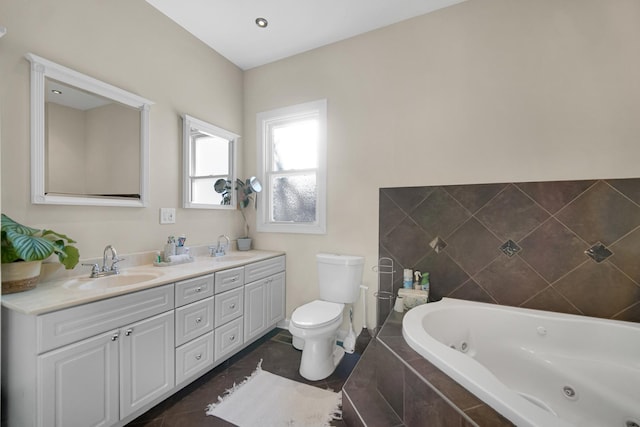 bathroom with tile patterned flooring, vanity, toilet, and tiled bath