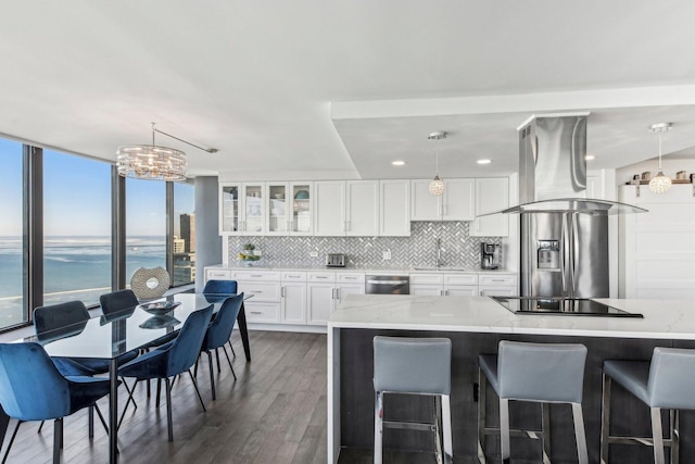 kitchen featuring pendant lighting, island exhaust hood, white cabinets, appliances with stainless steel finishes, and a water view