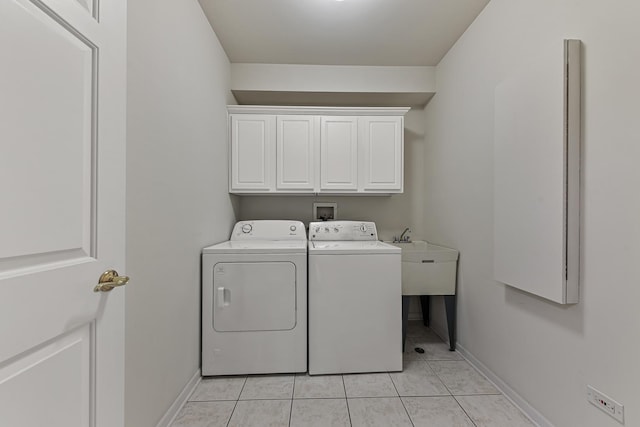 clothes washing area featuring washing machine and clothes dryer, light tile patterned floors, and cabinets