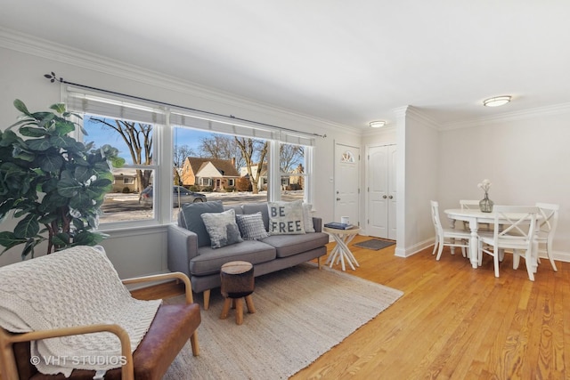 living room featuring a wealth of natural light, ornamental molding, and light hardwood / wood-style flooring