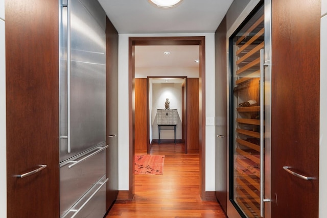 corridor with light wood-type flooring and wine cooler