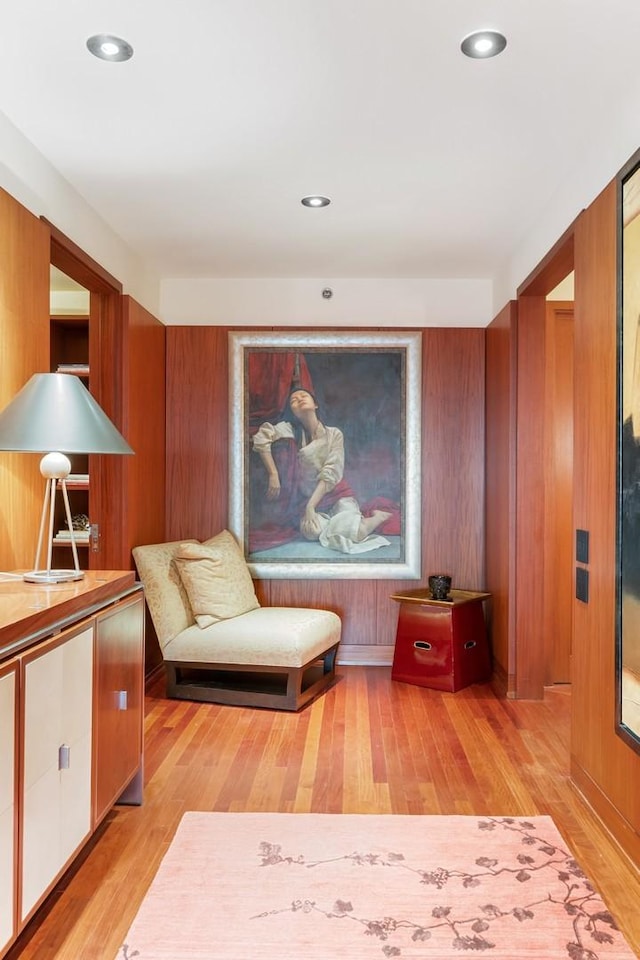 living area featuring wood walls and light hardwood / wood-style floors