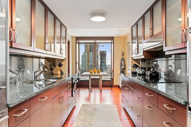 kitchen featuring black electric stovetop, dark stone counters, and light wood-type flooring