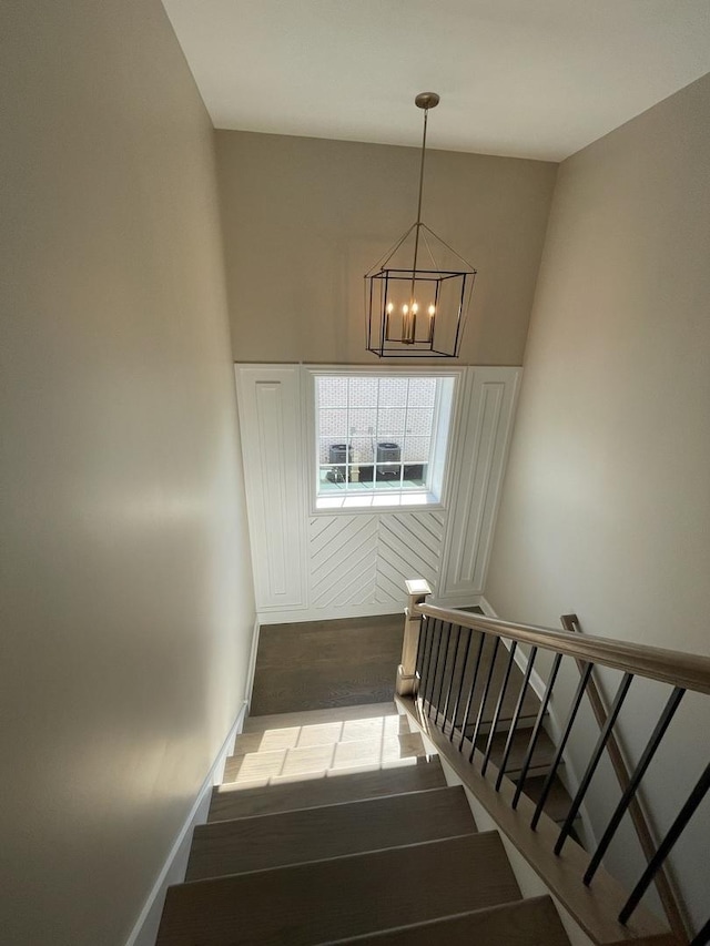 stairs with hardwood / wood-style flooring, a high ceiling, and an inviting chandelier