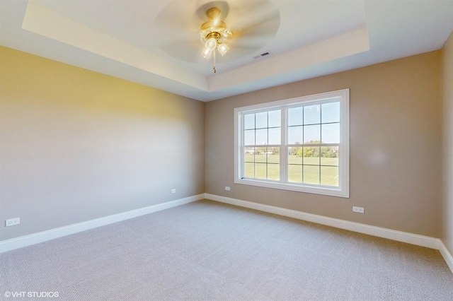 unfurnished room with carpet floors, a tray ceiling, and ceiling fan