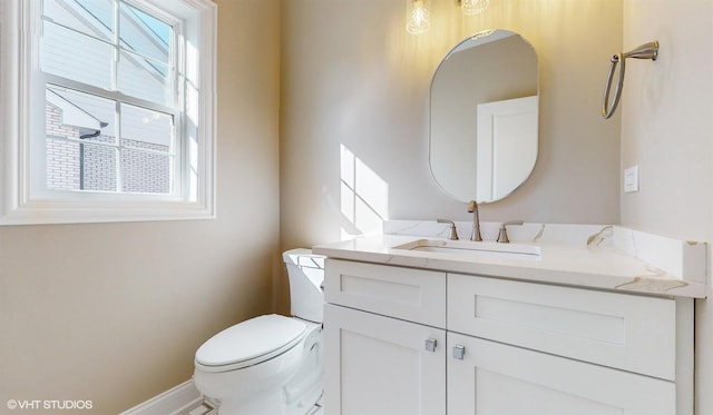 bathroom with plenty of natural light, vanity, and toilet