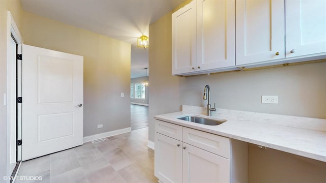 kitchen with white cabinets, light stone counters, and sink