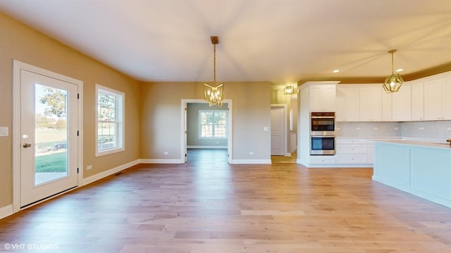 kitchen with white cabinetry, tasteful backsplash, a notable chandelier, pendant lighting, and light wood-type flooring