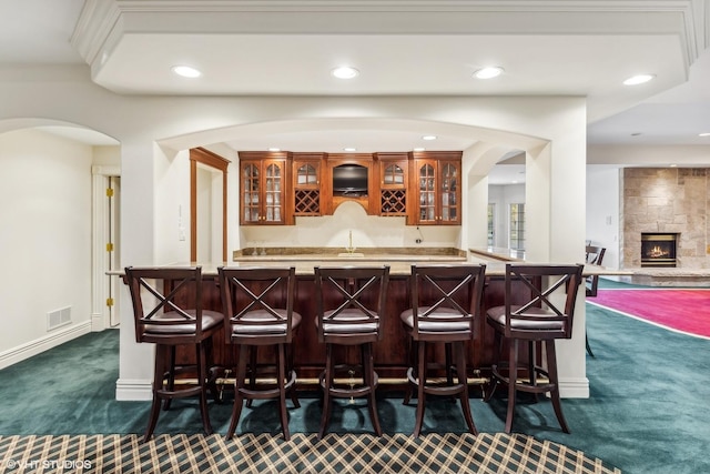 bar featuring dark carpet, a stone fireplace, and sink