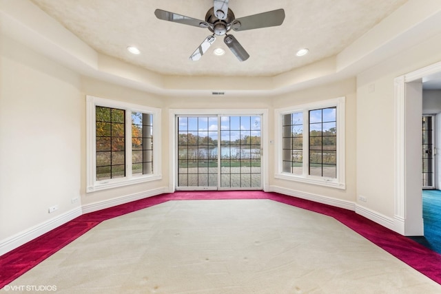 interior space with ceiling fan and a raised ceiling