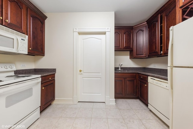 kitchen with dark stone countertops, white appliances, and sink