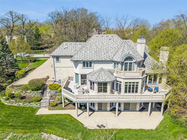 rear view of property featuring a yard, a balcony, cooling unit, and a patio