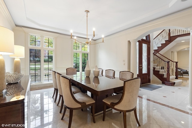 dining space featuring a raised ceiling, ornate columns, crown molding, and an inviting chandelier