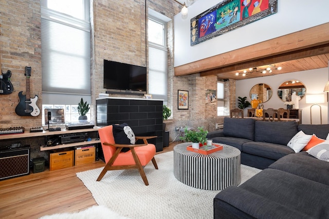 living room featuring a high ceiling, beamed ceiling, and light hardwood / wood-style flooring