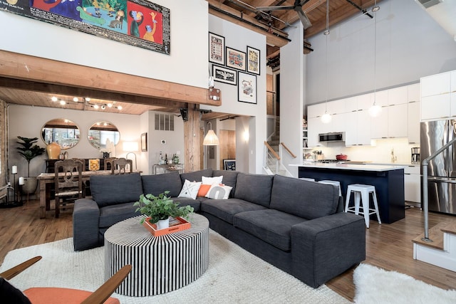 living room featuring beamed ceiling, light hardwood / wood-style floors, and a high ceiling