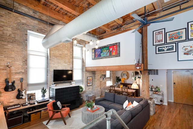 living room featuring brick wall, beamed ceiling, wood-type flooring, a high ceiling, and wooden ceiling