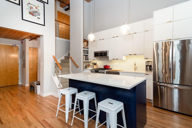 kitchen featuring a kitchen island, decorative light fixtures, white cabinetry, a kitchen breakfast bar, and stainless steel appliances