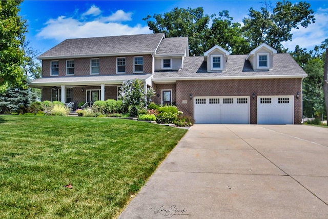 colonial-style house with covered porch, a garage, and a front lawn