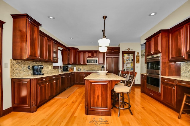 kitchen with stainless steel appliances, sink, a center island, hanging light fixtures, and a breakfast bar area