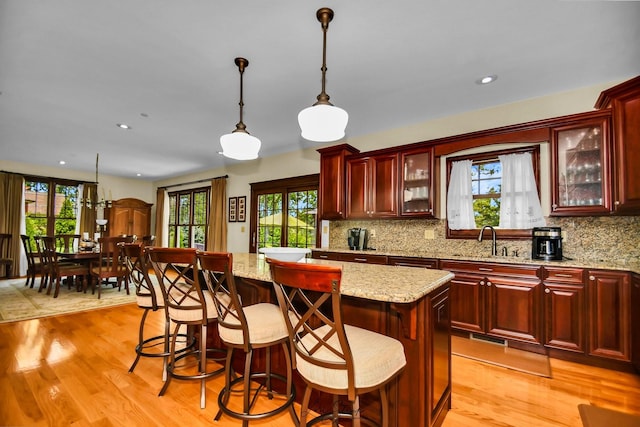 kitchen featuring a center island, light wood-type flooring, sink, and hanging light fixtures