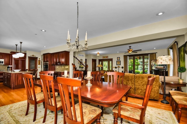 dining space featuring ceiling fan with notable chandelier and light wood-type flooring