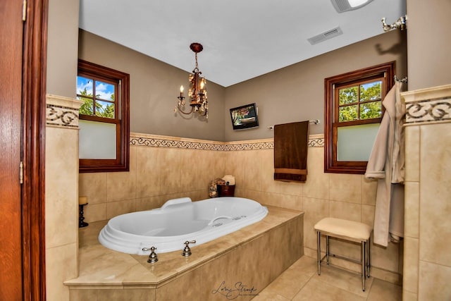 bathroom with tile patterned flooring, tiled bath, tile walls, and a chandelier