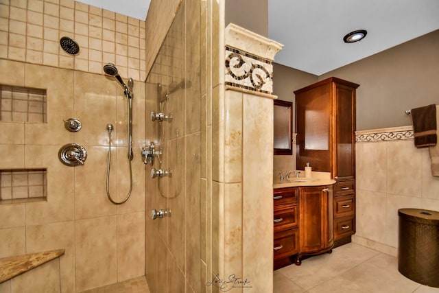 bathroom featuring tile patterned flooring, vanity, a tile shower, and tile walls