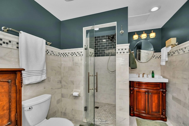 bathroom featuring vanity, toilet, a shower with shower door, and tile walls