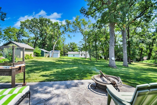 view of yard with a storage unit, an outdoor fire pit, and a patio