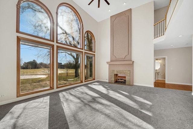 carpeted living room featuring a high end fireplace, high vaulted ceiling, and ceiling fan