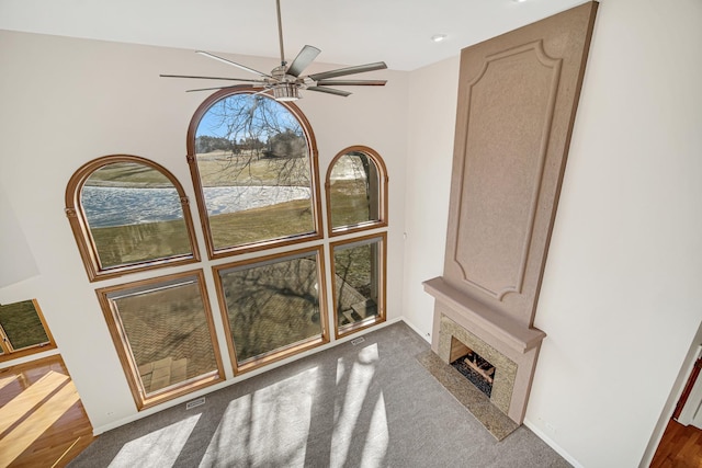 interior space featuring ceiling fan, dark carpet, and a fireplace